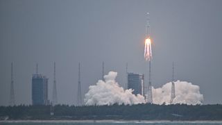 a white rocket lifts off through a greyish-blue sky 