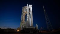 a large white rocket sits vertical on a launch pad at night