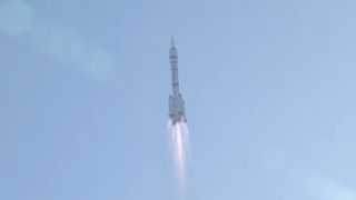 a white rocket launches into a blue sky