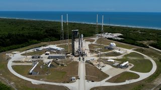 long-distance view of a rocket standing on a launch pad with the ocean in the background