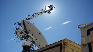 a white satellite dish points upward into a clear sky