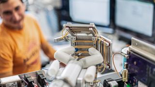 a robotic hand-like device reaching towards rubber bands in a lab